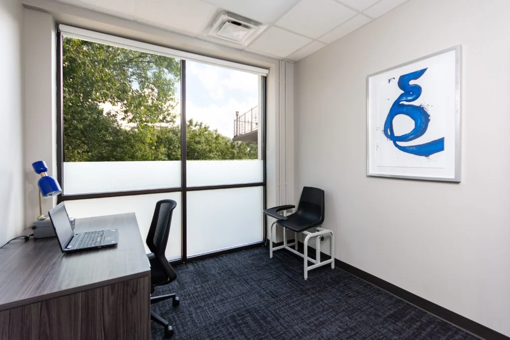 A private office with a desk, laptop, and a blue chair.