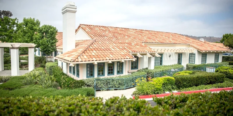 A rehab facility with a terracotta roof and lush landscaping.
