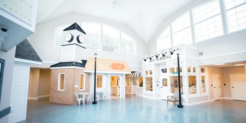 Bright indoor common area with café and mock storefronts