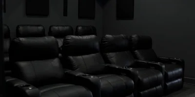 A dark home theater with black reclining chairs.