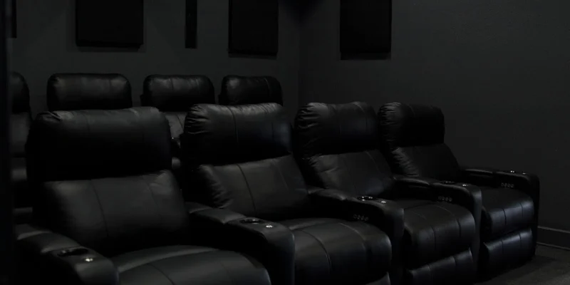 A dark home theater with black reclining chairs.