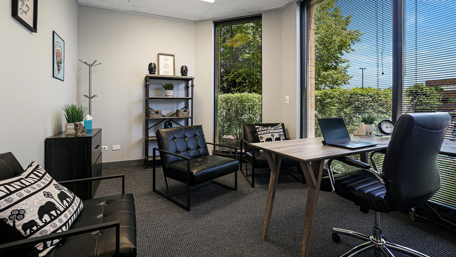 Office with black chairs, desk, and large windows.