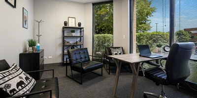 Office with black chairs, desk, and large windows.