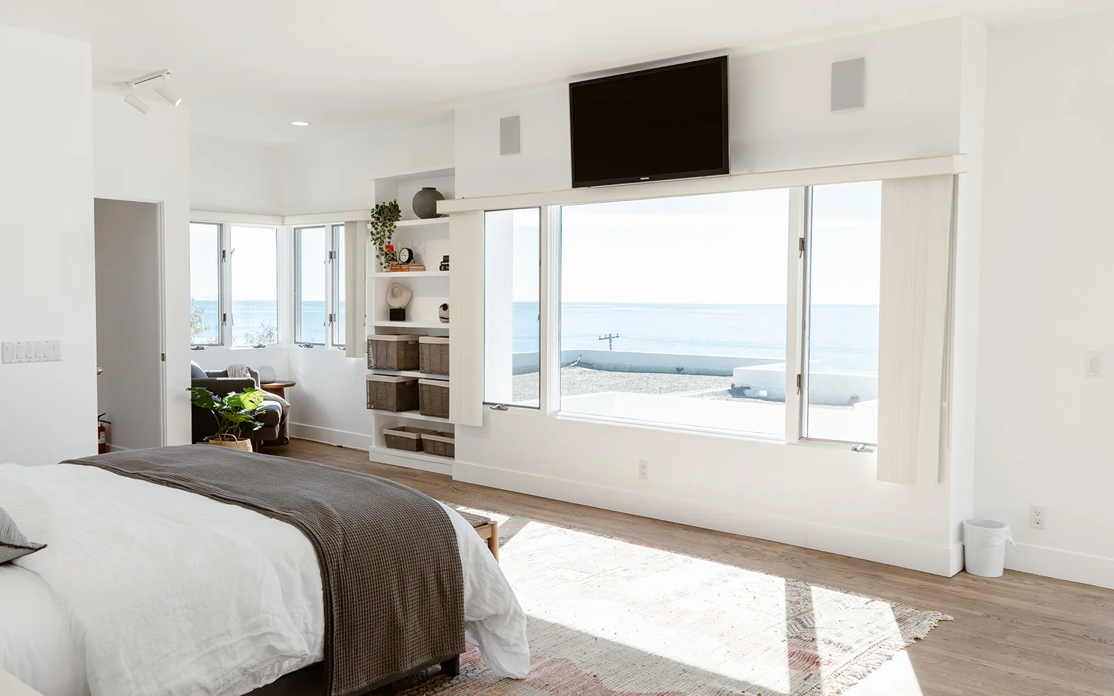  Bright bedroom with ocean views, modern decor, and built-in shelving.