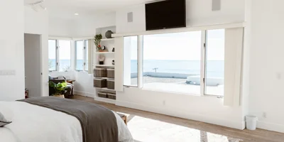  Bright bedroom with ocean views, modern decor, and built-in shelving.