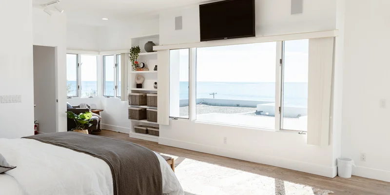  Bright bedroom with ocean views, modern decor, and built-in shelving.