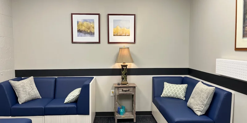 A seating area with blue cushioned sofas and framed artwork.