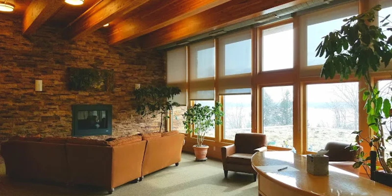 Reception area with seating and a desk next to large windows.