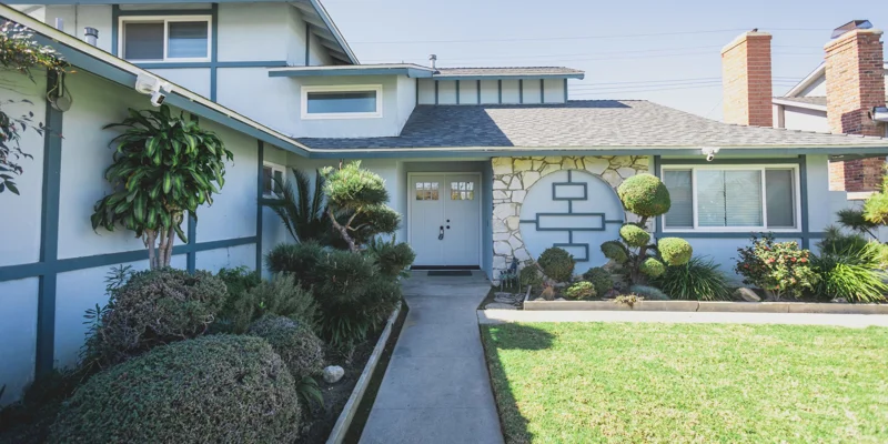 The exterior of a blue and white rehab facility with a landscaped front yard.