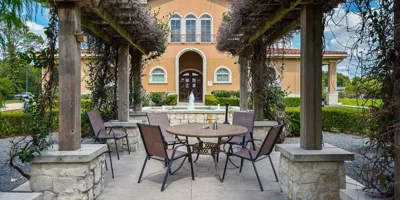 a wooden pergola, surrounded by greenery, and a fountain.