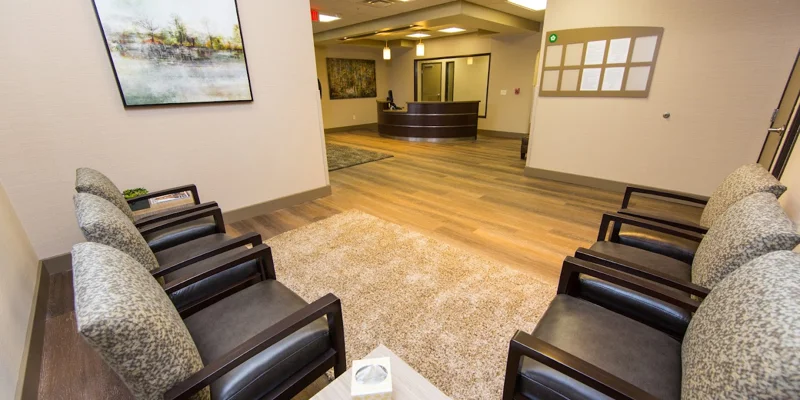 Reception area with a circular front desk and seating area with black chairs