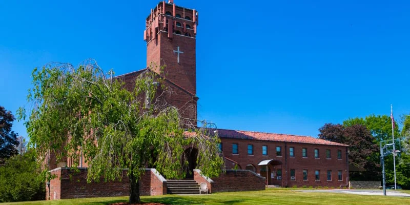 Exterior of red-brick facility with a lan and walkway to entrance.