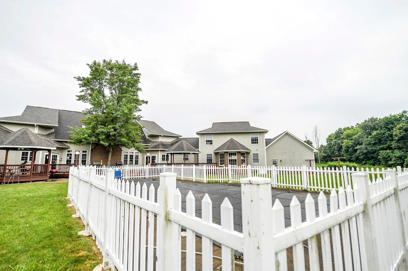 Outdoor fenced-in pool area with a wooden deck and gazebos.