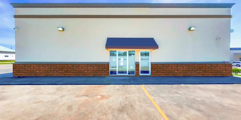 The exterior of a rehab facility with glass doors and an awning.