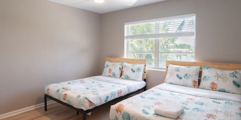 Two beds in bright room with palm tree views