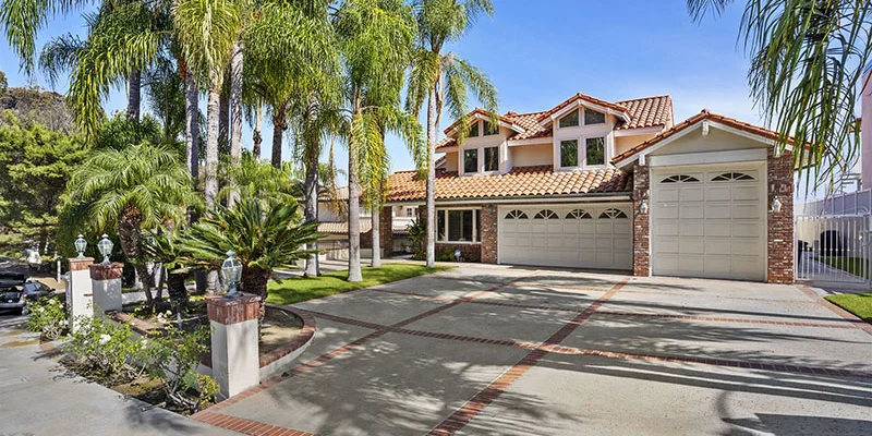 A large rehab facility with a driveway lined by tall palm trees.