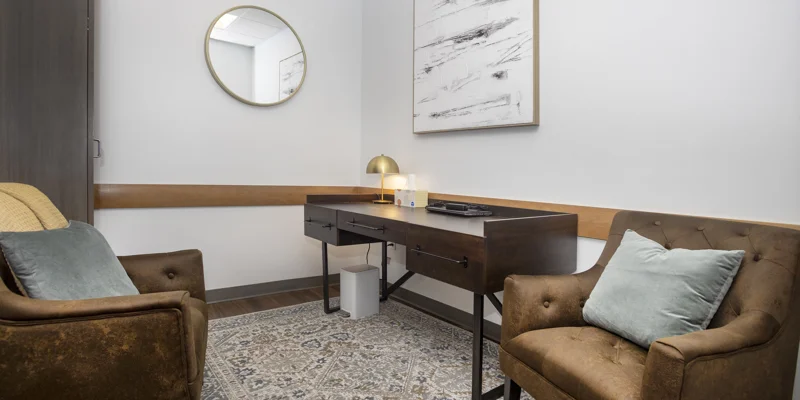 Office space with two arm chairs and a desk.