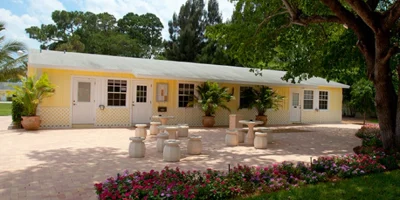 Yellow building with outdoor seating and lush greenery.