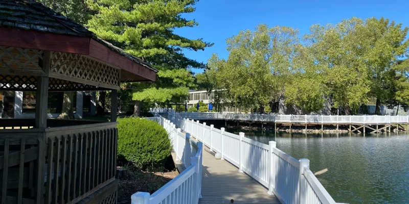 Boardwalk lined with white railings over pond.