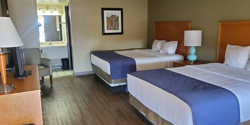 Room with two double beds, wooden furniture, and a framed picture