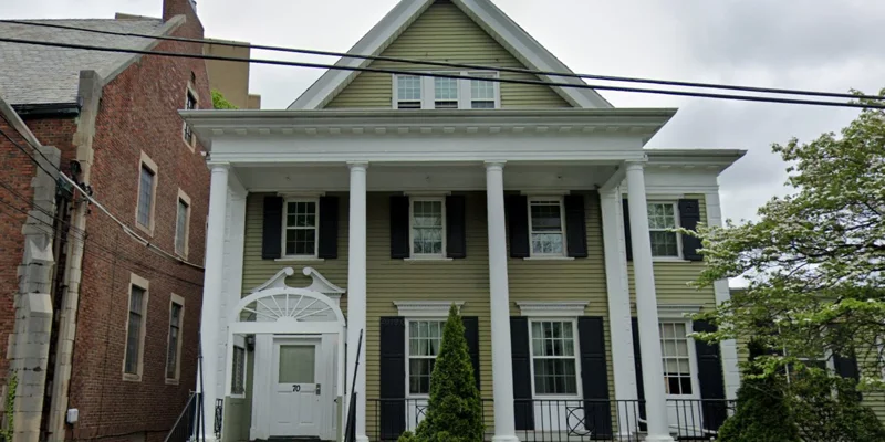 Front view of a traditional building with pillars and green shutters, providing a classic residential feel.