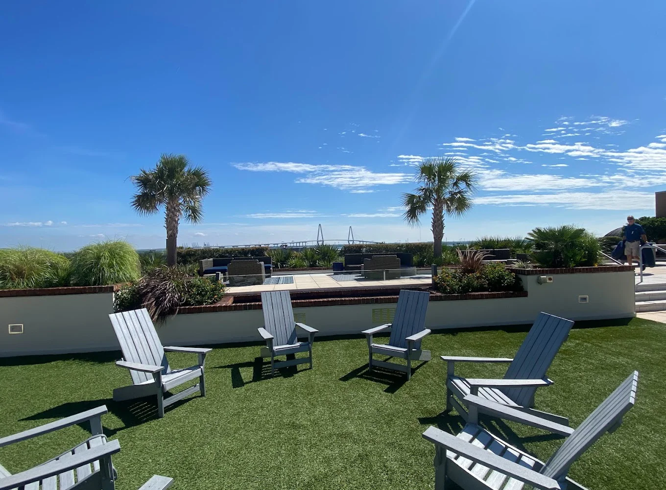 Outdoor seating area with Adirondack chairs and palm trees.