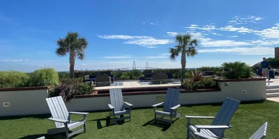Outdoor seating area with Adirondack chairs and palm trees.