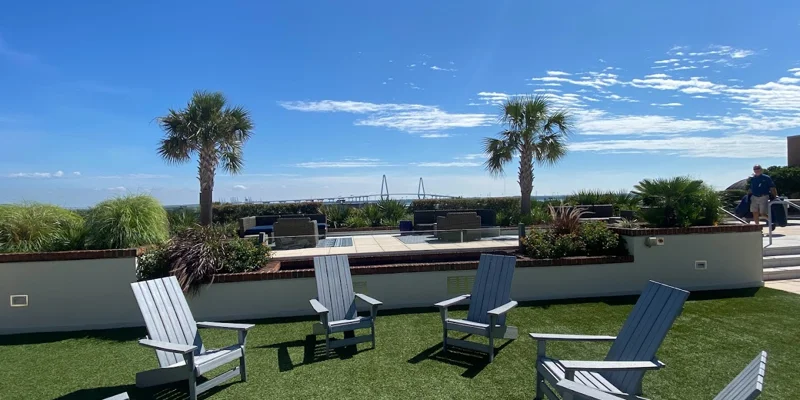 Outdoor seating area with Adirondack chairs and palm trees.