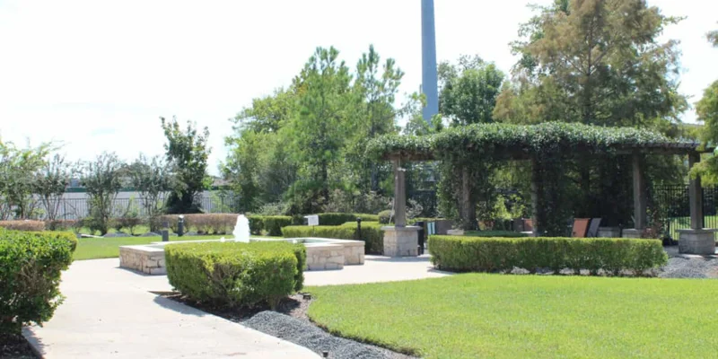 Outdoor garden with a fountain, seating area aroung greenery.