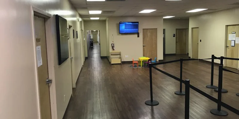 Interior hallway with wooden flooring, doors, a TV, and a waiting area.
