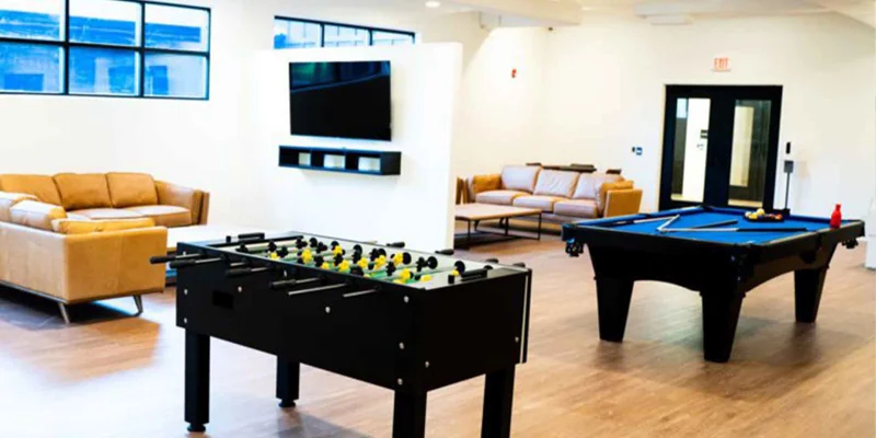 A recreation room with a foosball table, pool table, and seating