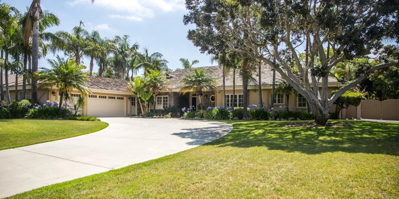 A rehab center with a lush front yard and palm trees.