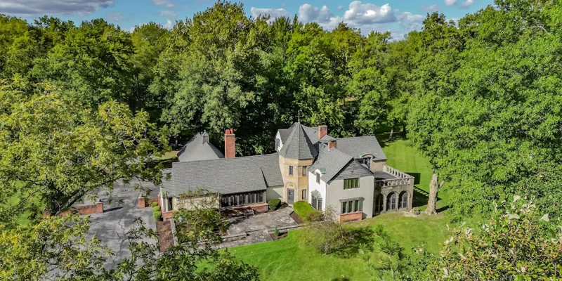 Aerial view of a Tudor-style rehab center surrounded by trees.