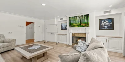 A common room with a fireplace, whiteboard, and cozy seating.