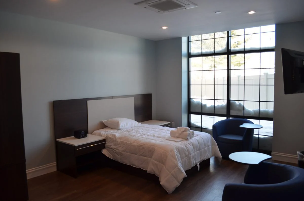 Minimalist bedroom with a large window and modern furnishings.