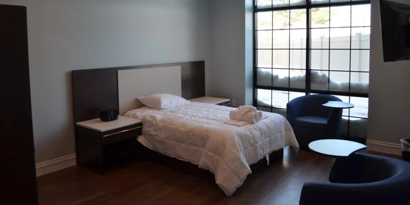 Minimalist bedroom with a large window and modern furnishings.