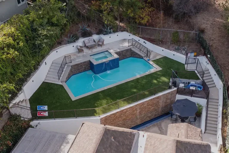 Backyard pool area with a spa and seating.