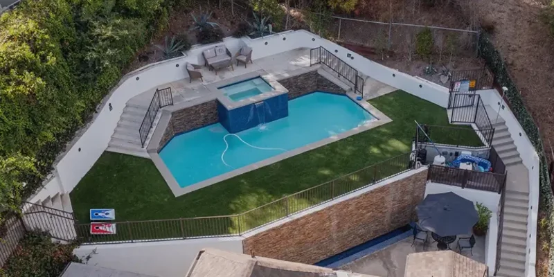 Backyard pool area with a spa and seating.