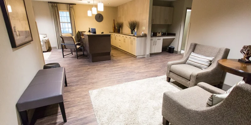 A common area with a kitchenette, seating, and warm decor.