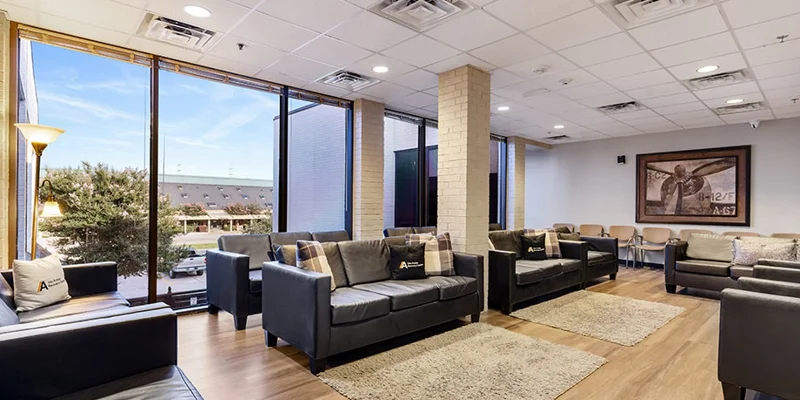 Large waiting room with black leather couches and floor-to-ceiling windows