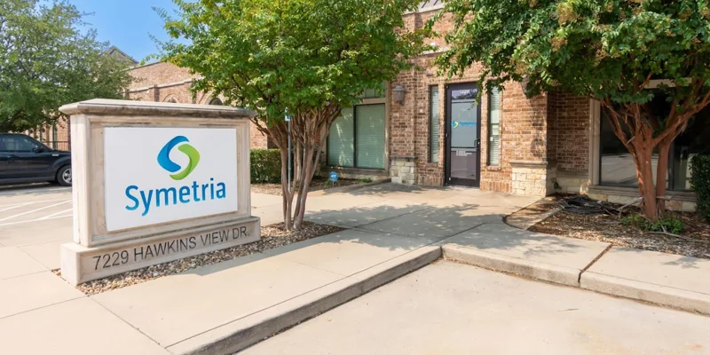 Exterior of Symetria Recovery with signage and trees.