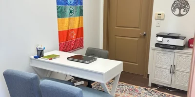 Cozy office space with a white desk and two chairs.