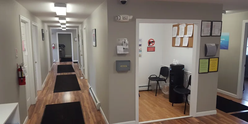 Hallway to offices with waiting room with chairs.