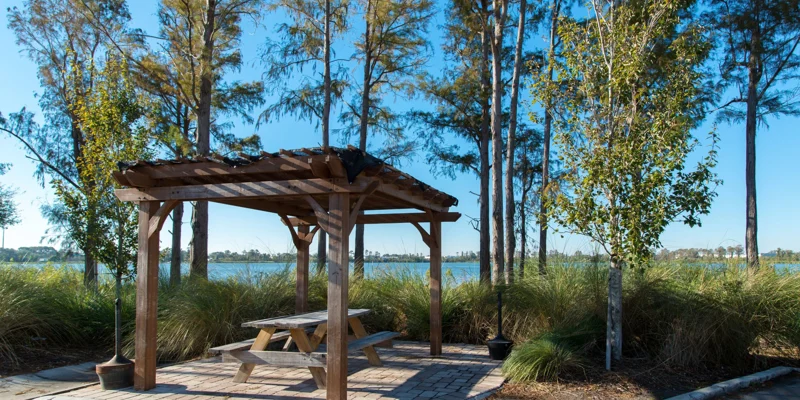 A serene outdoor seating area with a pergola overlooking a lake.