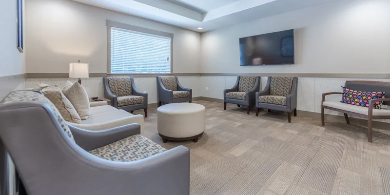 Modern waiting area with gray chairs, a TV, and soft lighting.