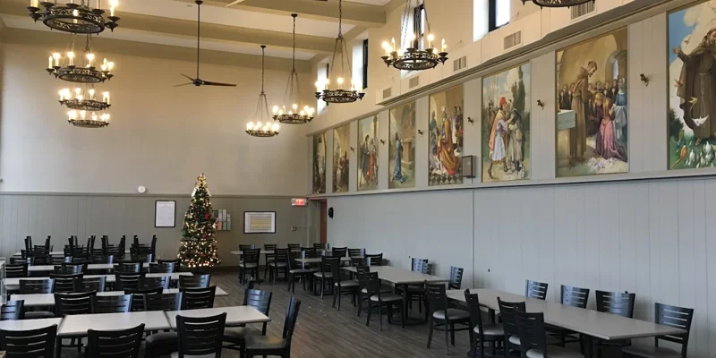 Dinning hall with long tables and chairs with wall decor. 