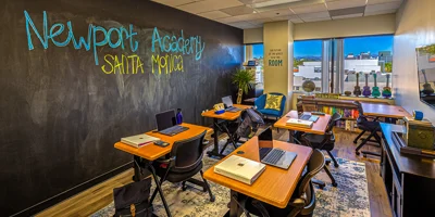 Classroom with a chalkboard wall and desks.