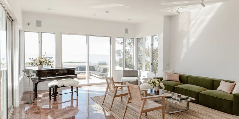 Spacious living room with ocean views, green sofa, and grand piano.