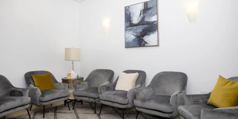  group therapy room with modern gray armchairs and abstract wall art