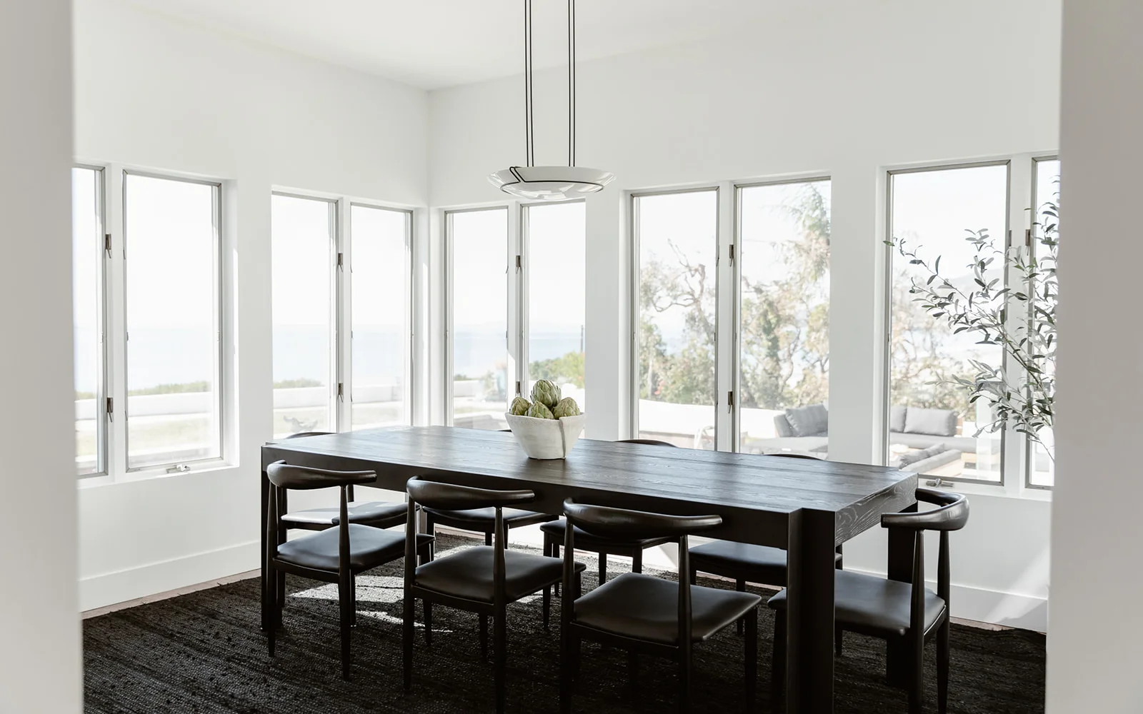 Minimalist dining room with large windows and ocean views.